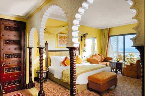 Innenansicht eines Zimmers im Jumeirah Al Qasr Hotel mit einem großen Bett und orientalischen Möbeln.