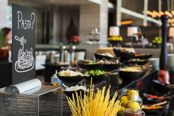 Buffet-Tisch im Pullman Dubai Downtown Hotel mit verschiedenen Speisen und einem Schild, das Pasta anbietet.