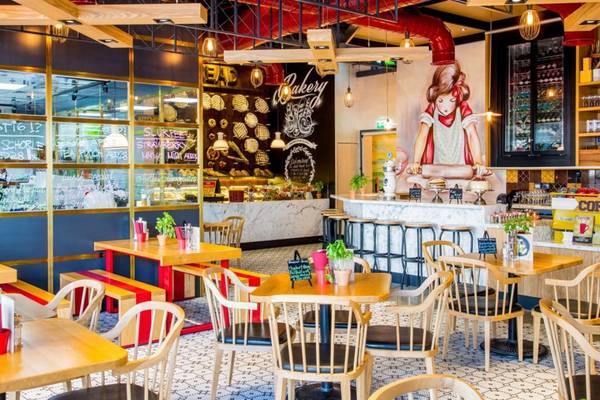Innenansicht des Restaurants im Pullman Dubai Downtown mit Tischen, Stühlen und einer Wandmalerei.