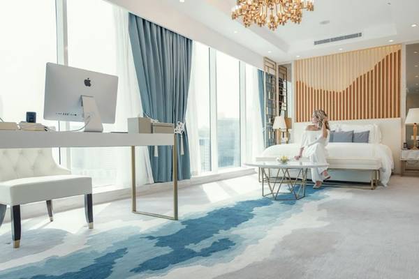Frau in weißem Kleid sitzt auf Tisch im luxuriösen Hotelzimmer von Pullman Dubai Downtown