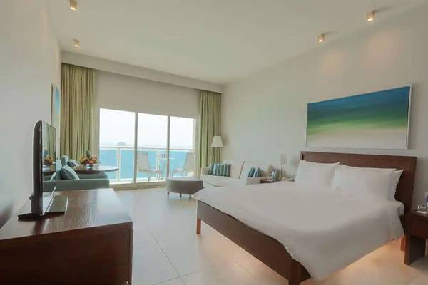 Ein modernes Hotelzimmer im Radisson Blu Resort, Fujairah, mit Blick auf das Meer von einem großen Fenster aus.