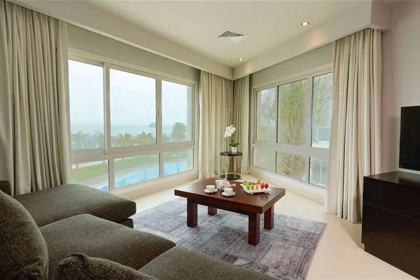 Wohnzimmer im Radisson Blu Resort, Fujairah mit großem Fenster, Couch, Tisch und Fernseher.