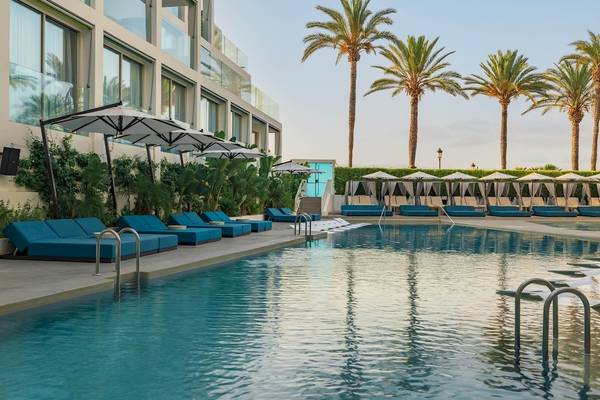 Außenpool des W Ibiza Hotels mit blauen Liegen und Sonnenschirmen