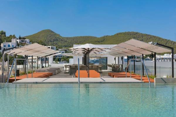 Poolterrasse des W Ibiza Hotels mit Sonnenliegen und Tischen unter Sonnenschirmen