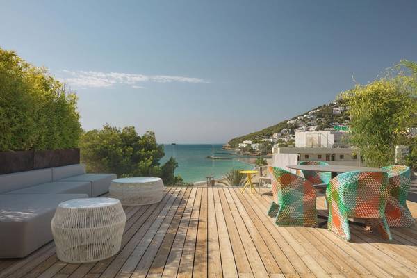 W Ibiza Hotel Terrasse mit Blick auf das Meer und einen Berg im Hintergrund.