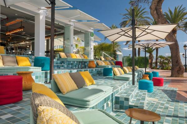 Loungebereich des W Ibiza Hotels mit bunten Kissen und Sonnenschirmen.