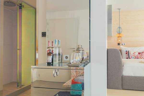 W Ibiza Hotelzimmer mit Spiegelschrank, Flaschen und Bett im Hintergrund