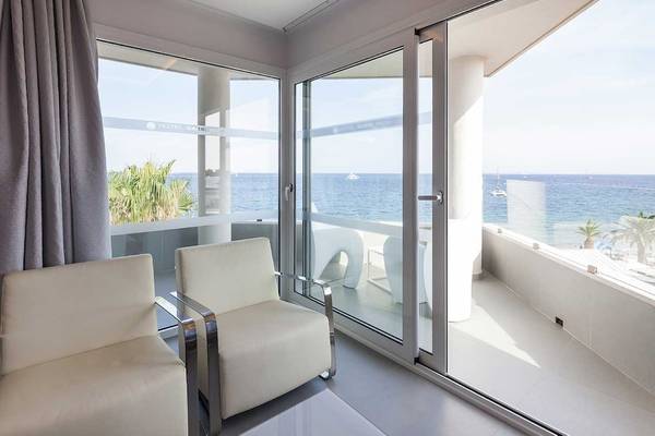Ein Balkon mit Meerblick im Sentido Garbi Ibiza & Spa Hotel, mit zwei weißen Stühlen und Panoramafenstern.