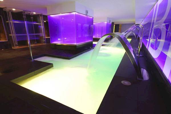 Schwimmbecken im Sentido Garbi Ibiza Spa mit farbigen Lichtern und Wasserstrahlen.