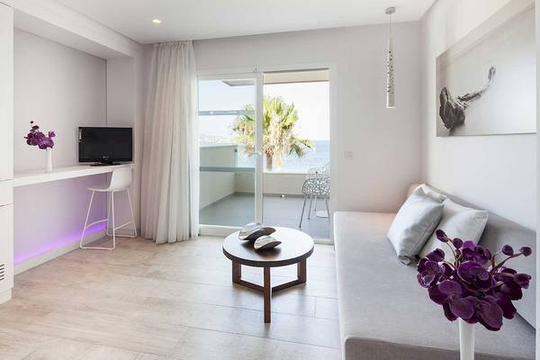 Wohnzimmer des Sentido Garbi Ibiza & Spa Hotels mit Blick auf das Meer und Palmen.