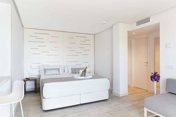Schlafzimmer im Sentido Garbi Ibiza & Spa mit weißem Bett, grauen Kissen und einem Nachttisch.