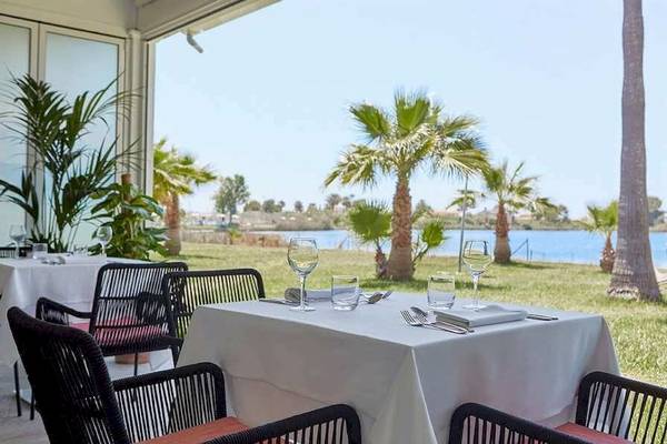 Außenrestaurant des Universal Aparthotel Elisa mit Blick auf den See und Palmen.