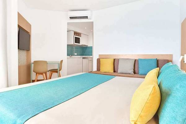 Schlafzimmer im Universal Aparthotel Elisa mit Bett, Kissen, Couch, Fernseher und Küche