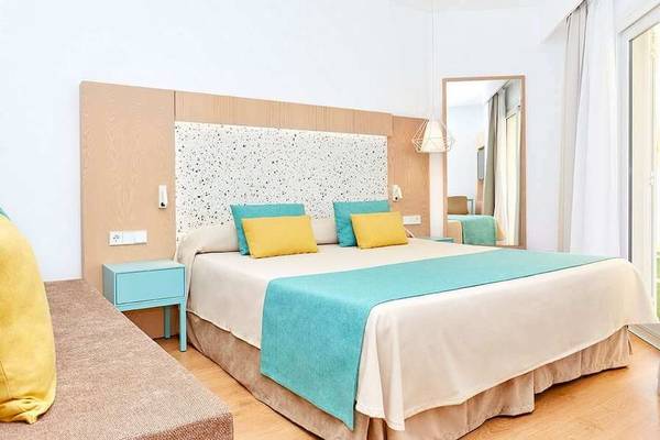 Schlafzimmer im Universal Aparthotel Elisa mit Bett, Nachttischen und Spiegel.