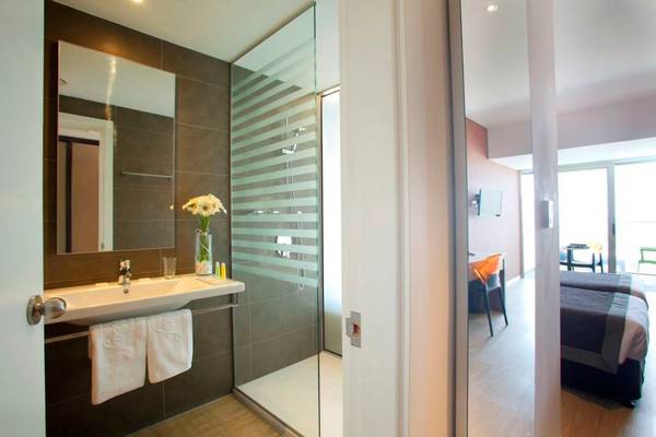 Badezimmer im Faros Hotel Ayia Napa mit Dusche, Spiegel und Waschbecken.