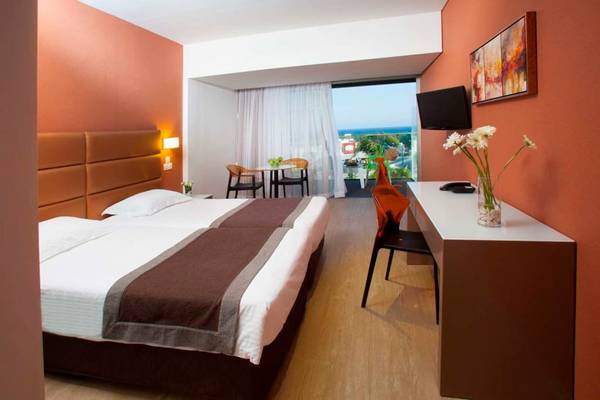 Doppelzimmer im Faros Hotel Ayia Napa mit zwei Betten, Schreibtisch und Blick auf das Meer.