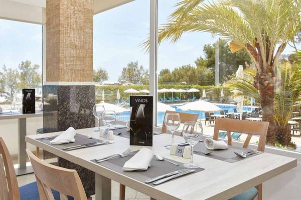 Innenansicht des Castell Royal Hotels mit Tisch im Restaurant, Blick auf den Poolbereich.