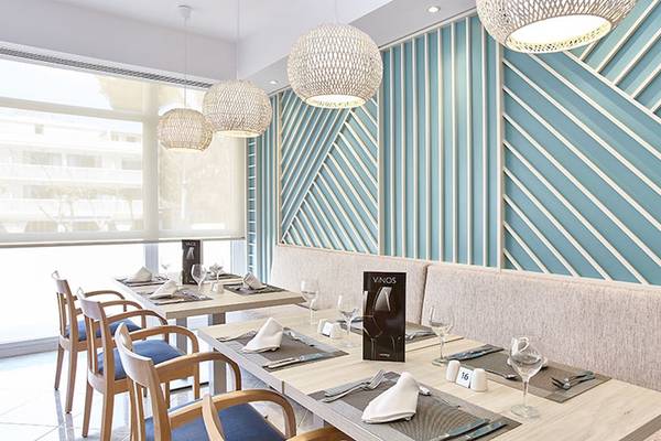 Innenansicht des Restaurants im Castell Royal Hotel mit blauen Wänden und Holztischen.