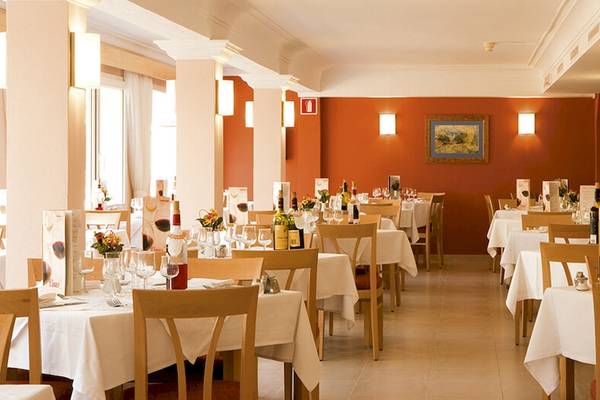 Innenansicht des Restaurants im Bikini Hotel mit geräumigen Tischen und Stühlen, dekorativ beleuchteten Wänden und kunstvollen Wandgemälden.
