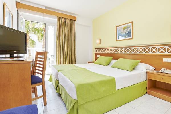 Doppelzimmer im Bikini Hotel mit zwei Betten, grünen Kissen und weißer Bettwäsche.