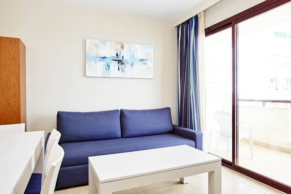 Innenansicht eines Wohnzimmers mit einem blauen Sofa, einem weißen Tisch und einer modernen Wanddekoration.