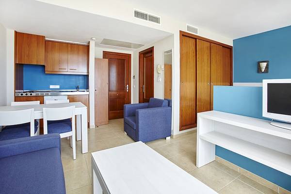 Innenbereich des Bikini Hotels mit Wohnzimmer, Esstisch, Fernseher und Küchenbereich.