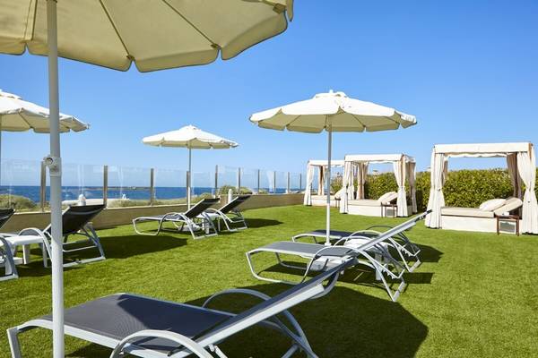 Terrasse des Grand Leon & Spa Hotels mit Liegen, Sonnenschirmen und Blick auf das Meer
