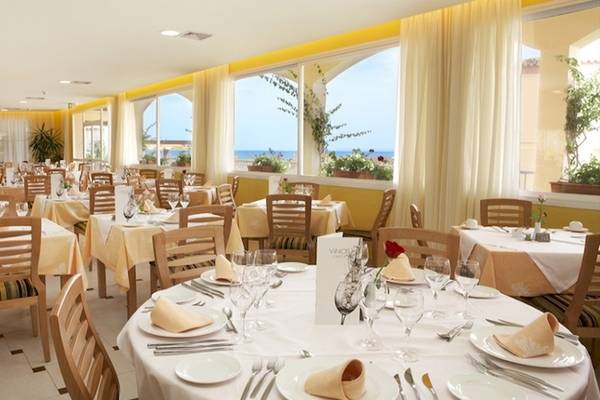 Innenansicht des Restaurants im Grand Leon & Spa Hotel mit gedeckten Tischen und Stühlen, Blick auf das Meer.