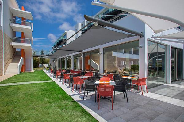 Außenbereich des Faros Hotel Ayia Napa mit Tischen und Stühlen unter Sonnensegeln.
