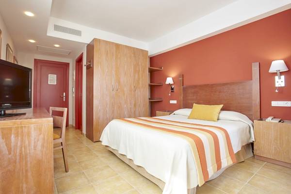 Innenansicht eines Hotelzimmers im Grand Leon & Spa mit Bett, Fernseher und Möbeln.