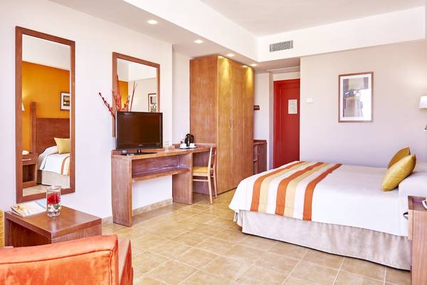 Hotelzimmer im Grand Leon & Spa mit Bett, Fernseher, Schreibtisch und Spiegel.