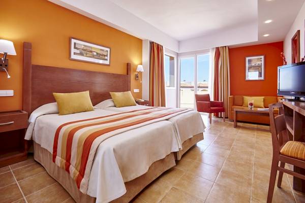 Doppelbett-Zimmer im Grand Leon & Spa Hotel mit orangefarbenen Wänden und türkisfarbenen Bettdecken.
