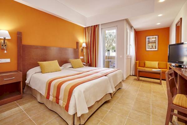 Doppelbettzimmer im Grand Leon & Spa Hotel mit orangefarbenen Wänden und modernen Möbeln.