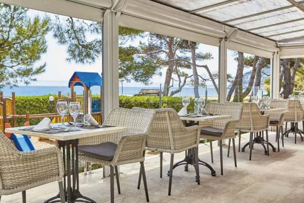 Außenterrasse des Laguna Hotels mit Blick auf das Meer und eine Kinderspielanlage.