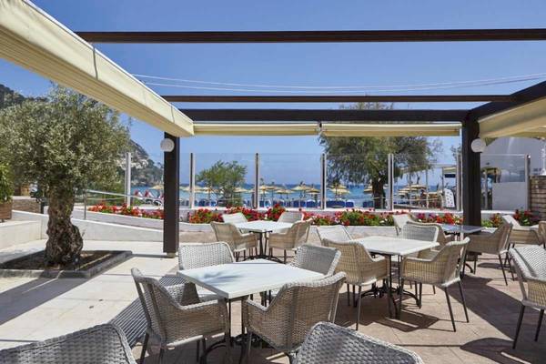 Terrasse des Laguna Hotels mit Blick auf das Meer und umgeben von weißen Stühlen und Tischen.