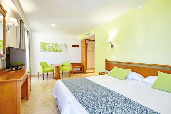 Innenansicht eines Doppelzimmers im Laguna Hotel mit hellem Interieur, einem Doppelbett, Fernseher, Tisch und Stühlen.