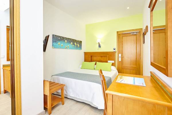 Ein helles Hotelzimmer im Laguna Hotel mit Bett, Schreibtisch und Dekoration.