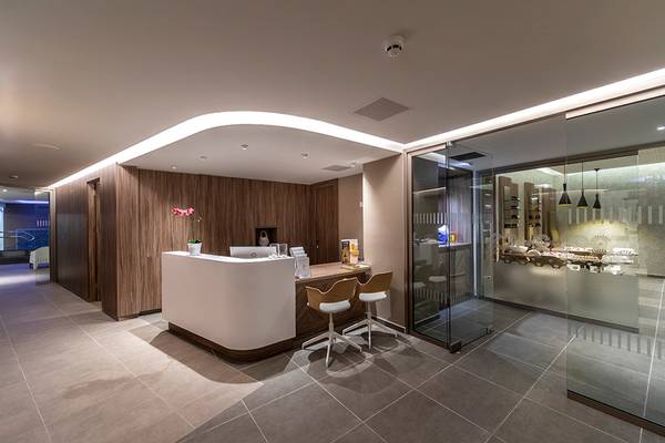 Lobby und Rezeption des Faros Hotel Ayia Napa mit modernem Design, hölzernen Wänden und einem Schreibtisch.
