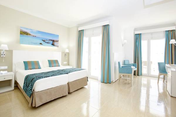 Innenansicht eines Doppelzimmers im Lido Park Hotel mit zwei Betten, blauen Vorhängen und Seeansicht.