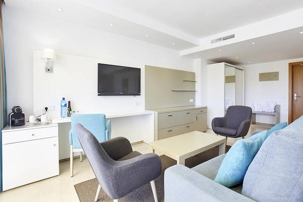 Wohnbereich im Lido Park Hotel mit Fernseher, Schreibtisch, Stühlen und Sofa.