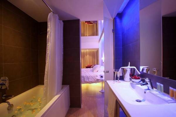 Badezimmer im Faros Hotel Ayia Napa mit Badewanne, beleuchteten Wänden und einem Blick auf das Bett