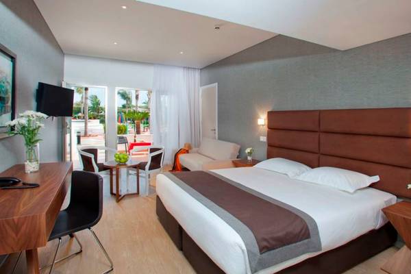 Hotelzimmer im Faros Hotel Ayia Napa mit Doppelbett, Schreibtisch und Balkonzugang.