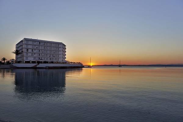 Abendlicher Untergang am Marques Hotel am Meer mit ruhigem Wasser und reflektierten Farben.