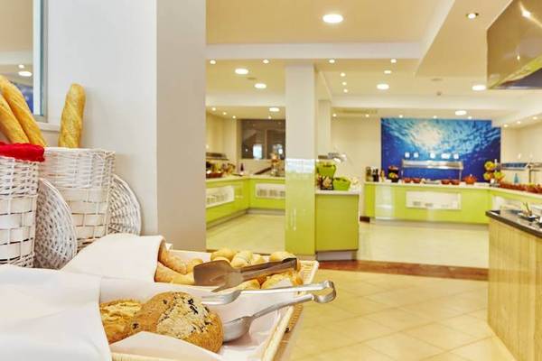 Frühstücksbuffet im Marques Hotel mit Brot und Gebäck in weißen Körben und Tischen.