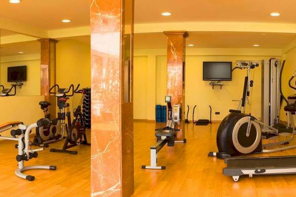 Fitnesscenter im Marques Hotel mit verschiedenen Trainingsgeräten und Fernsehgeräten an der Wand.