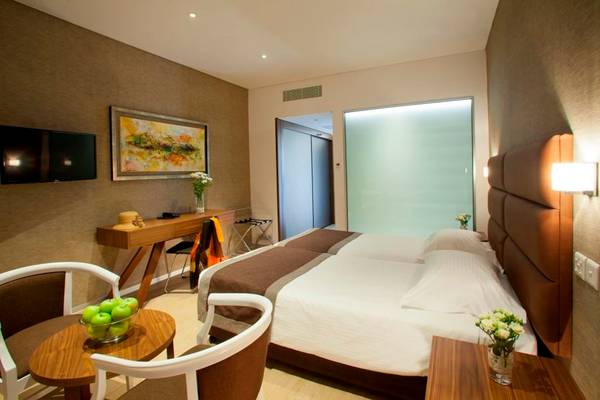 Schlafzimmer im Faros Hotel Ayia Napa mit zwei Betten, Tisch, Stühlen und Dekor.