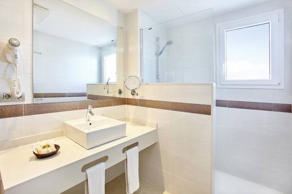 Modernes Badezimmer im Marques Hotel mit weißer Wandfliesen, einem Waschbecken und einem großen Spiegel.
