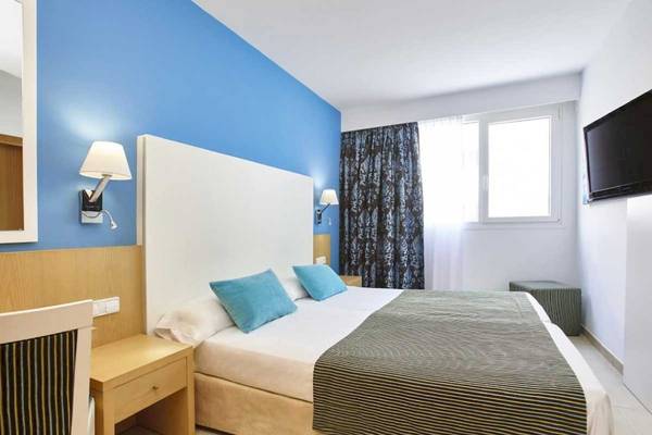Ein Zimmer im Marques Hotel mit blauen Wänden, einem Bett, Nachttischen und einer Fernseher.