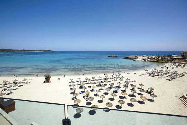 Aussicht auf den Strand des Perla Hotels mit vielen Sonnenschirmen und vielen Gästen.