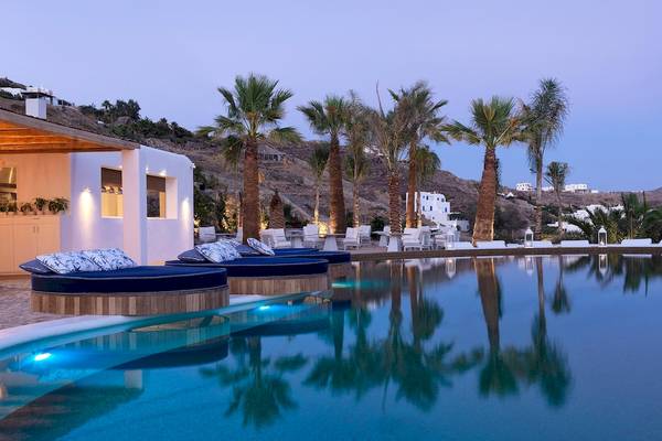 Poolbereich der Katikies Villas auf Mykonos mit Loungebetten und Palmen